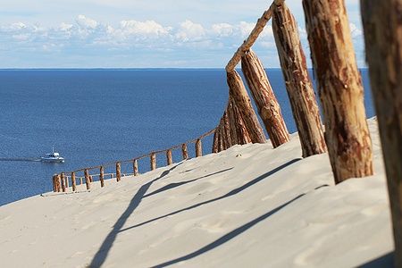 Dune sabbiose e staccionata di legno al Curonian Spit con il mare sullo sfondo.