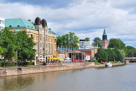 Argine del fiume Aura a Turku, Finlandia, con edifici storici e barche.