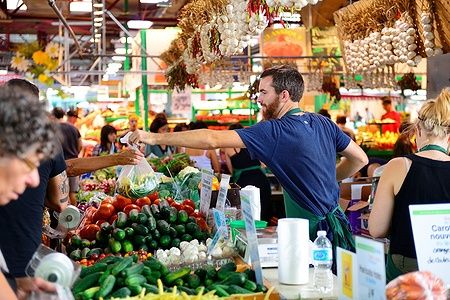 Scena vivace al Jean-Talon Market di Montreal con persone e prodotti freschi.