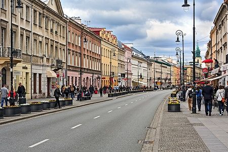 Nowy Świat a Varsavia con gente che passeggia tra edifici storici e negozi.