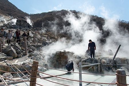 Persone osservano fumarole e sorgenti termali nella valle di Owakudani.