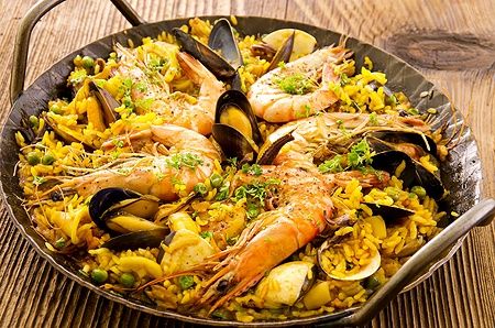Paella di mare in padella di ferro battuto con gamberi e cozze.