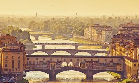 Veduta del Ponte Vecchio a Firenze al tramonto con il fiume Arno.