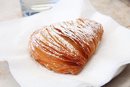 Sfogliatella napoletana con zucchero a velo su tovagliolo.