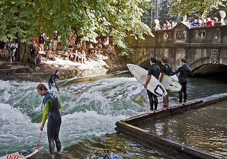 Surfisti e spettatori al canale di surfing nell'Englischer Garten a Monaco.