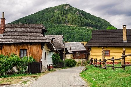 Villaggio storico di Vlkolínec in Slovacchia con case di legno e montagne sullo sfondo.