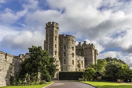 Castello di Windsor con giardino curato e cielo azzurro a nuvole.