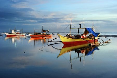 Tradizionali barche delle Filippine su acque calme in un paesaggio tropicale.