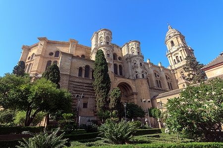 Cattedrale di Malaga con cielo azzurro e vegetazione circostante.