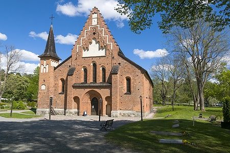 Chiesa medievale di Santa Maria a Sigtuna, in Svezia, con mattoni rossi e parco verde.