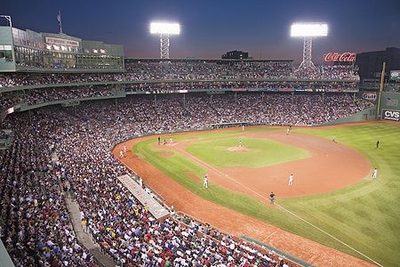 Partita serale di baseball al Fenway Park con una folla di spettatori.