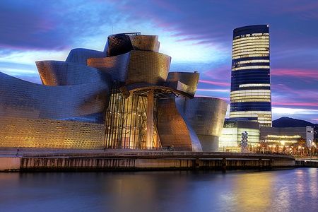 Il Guggenheim Museum e la Torre Iberdrola a Bilbao sotto un cielo al tramonto.