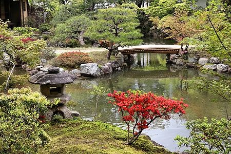 Giardino giapponese con un ponte di legno e azalee in fiore a Isuien Garden, Nara.