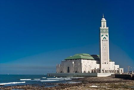 La Moschea di Hassan II a Casablanca si affaccia sull'Atlantico sotto un cielo blu.