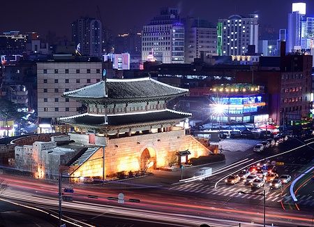 Namdaemun Gate illuminata di notte a Seoul con traffico di auto.