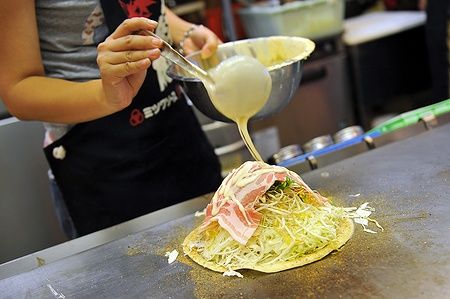 Preparazione di un okonomiyaki su una piastra calda a Hiroshima.