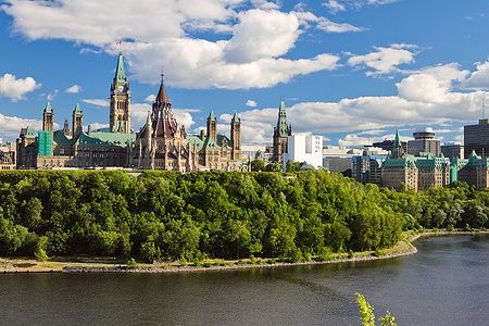 Parliament Hill a Ottawa con architettura gotica e il fiume Ottawa in primo piano.