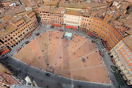 Vista aerea di Piazza del Campo a Siena, con edifici storici in terracotta.