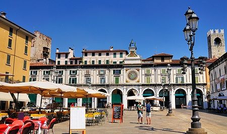 Piazza della Loggia a Brescia con caffè all'aperto e edifici storici.