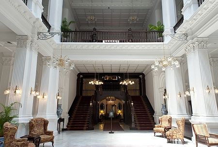 Ingresso e scale interne del Raffles Hotel a Singapore, con eleganti colonne.