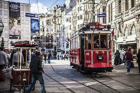 Storico tram rosso in movimento su una strada affollata di Istanbul.