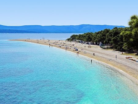 Spiaggia di Zlatni Rat con acque turchesi e persone sulla sabbia.