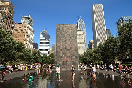 Persone si rinfrescano alla Crown Fountain con lo skyline di Chicago sullo sfondo.