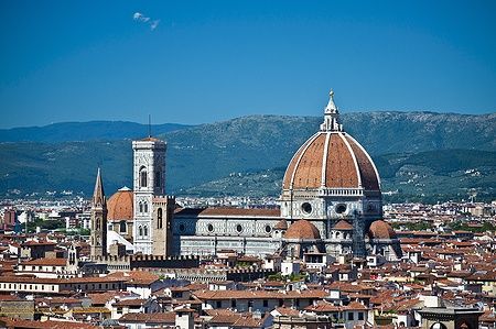 Vista del Duomo di Firenze da Piazzale Michelangelo con cielo blu e montagne sullo sfondo.