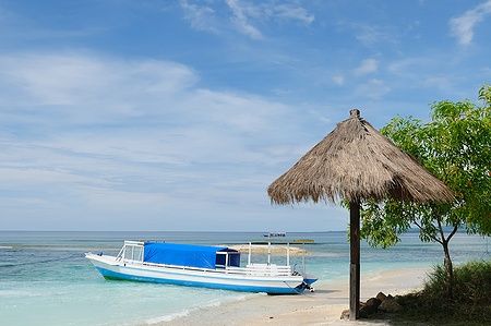 Barca bianca con copertura blu sulla spiaggia delle Gili Islands, Indonesia.