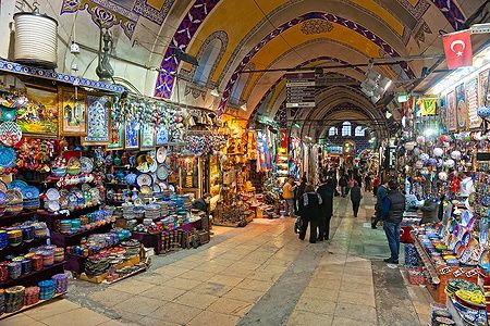 Interno del Grand Bazaar di Istanbul con negozi colorati e persone che passeggiano.