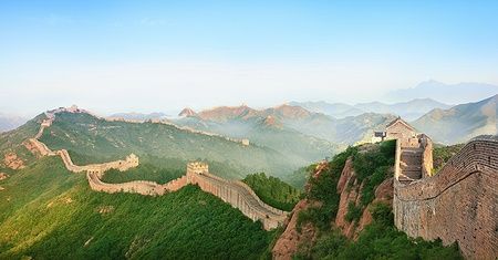 La Grande Muraglia Cinese si estende tra le colline sotto un cielo azzurro.