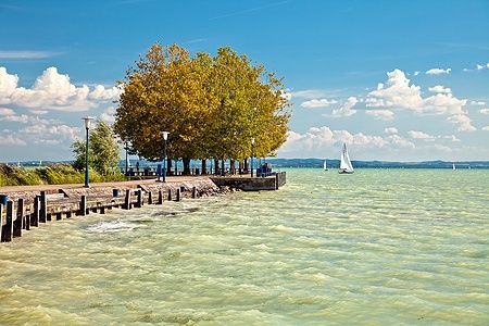 Molo sul lago Balaton in Ungheria con barca a vela e cielo azzurro.