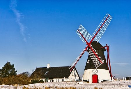 Mulino a vento su Mandø, vicino a Ribe, Danimarca, sotto un cielo azzurro.