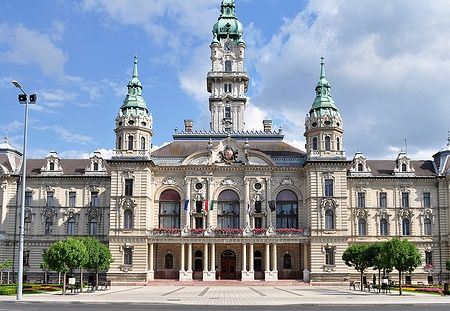 Il municipio di Győr con la sua facciata decorata e le torri sotto un cielo azzurro.