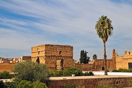 Le rovine del Palais El Badi a Marrakech con palme e cielo azzurro.