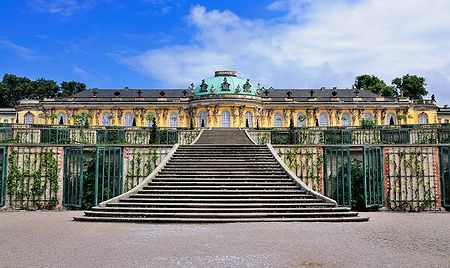 Il Palazzo di Sanssouci a Potsdam con gradinate e cielo soleggiato.
