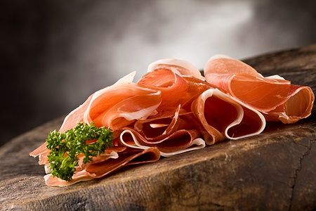 Fette di bacon con prezzemolo su tavolo di legno.