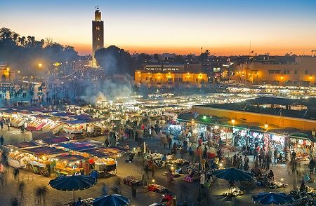 Piazza Djemaa el-Fna a Marrakech di notte, con bancarelle e folla presente.