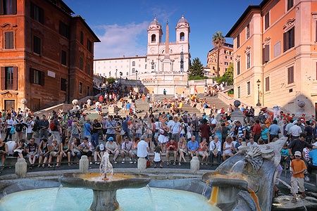 Persone sulla Piazza di Spagna a Roma con la scalinata di Trinità dei Monti.