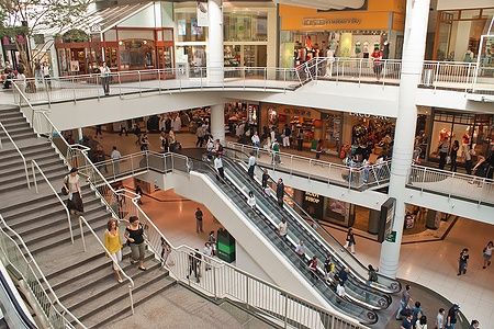 Interno del Toronto Eaton Center con persone che passeggiano e usano le scale mobili.