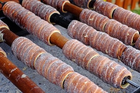 Trdelnik ceco tradizionale su spiedi di legno sopra carboni ardenti.