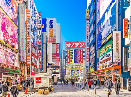 Strada di Akihabara a Tokyo con cartelloni pubblicitari e persone.