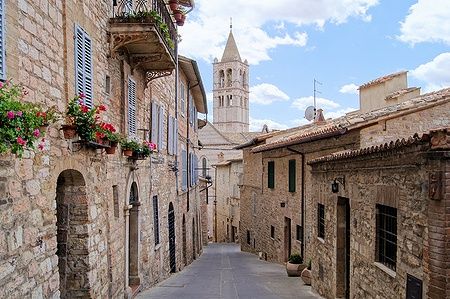 Strada medievale ad Assisi con la chiesa di Santa Chiara sullo sfondo.