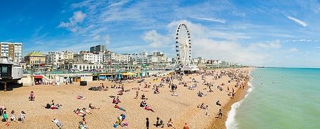 Spiaggia di Brighton con ruota panoramica e bagnanti in una giornata di sole.