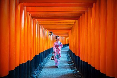 Donna in kimono al Fushimi Inari Shrine di Kyoto tra torii rossi.