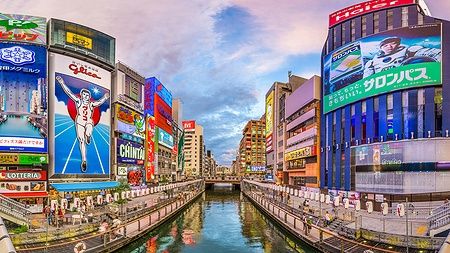 Panorama del canale Dotonbori a Osaka con insegne luminose e vita notturna.