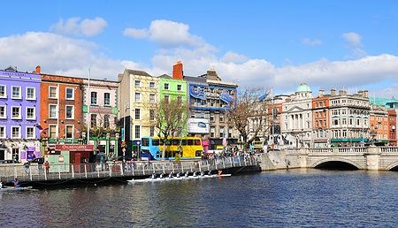 Turisti ammirano edifici colorati lungo le banchine del fiume Liffey a Dublino.