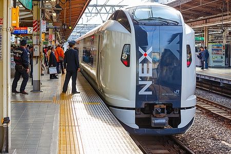 Narita Express alla stazione di Tokyo con passeggeri sulla piattaforma.