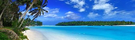 Laguna tropicale con acque turchesi e palme su una spiaggia di sabbia bianca.