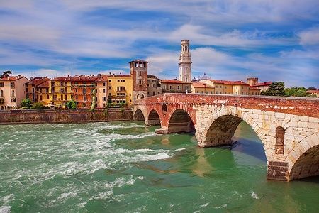 Ponte Pietra a Verona sopra il fiume Adige con edifici storici sullo sfondo.